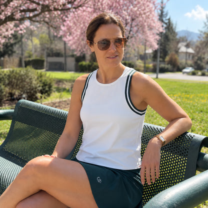 Mujer sentada usando la polera Porto Fino blanca con ribete esmeralda y falda verde Ophira